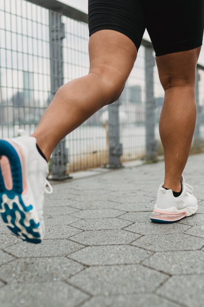 Close-up of legs jogging outdoors with urban backdrop, wearing athletic shoes.