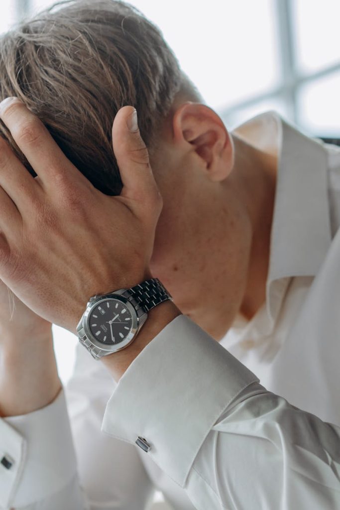 A business professional showing stress and fatigue with head in hands.