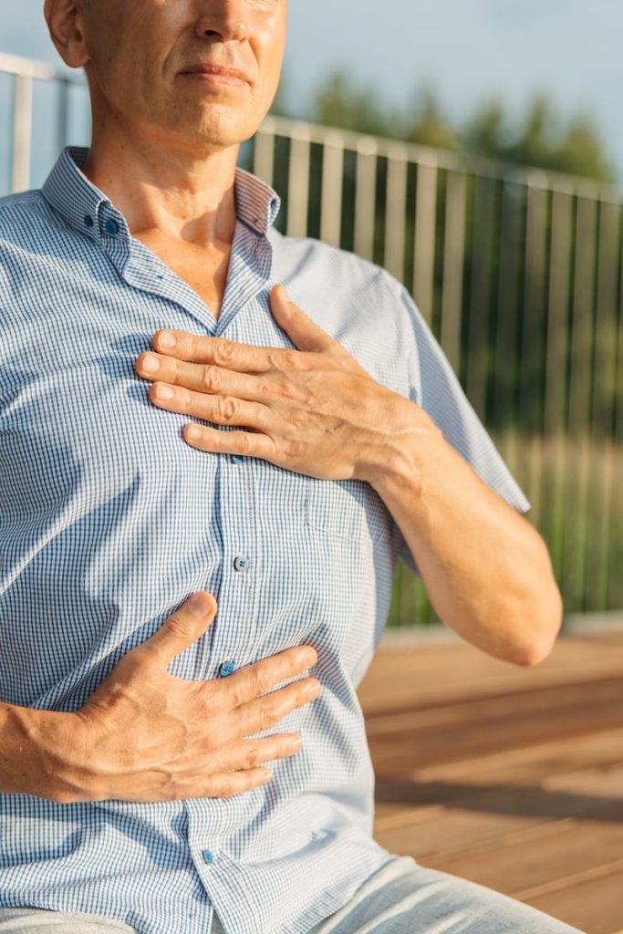 A man practicing relaxation with hands on chest and abdomen outdoors.